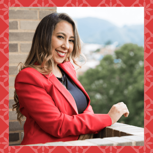 Coaching for Latinas client smiling confidently and wearing a red blazer.